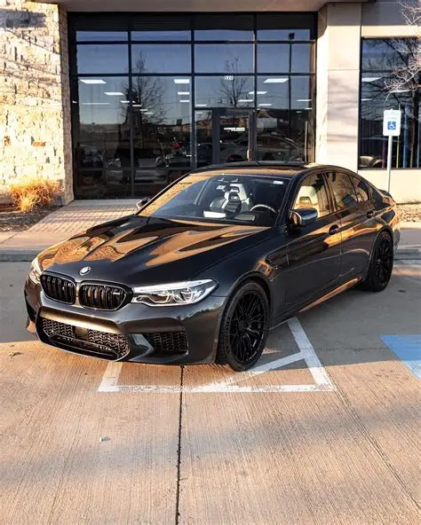Grijze BMW M5, drie kwart vooraanzicht bij een showroom