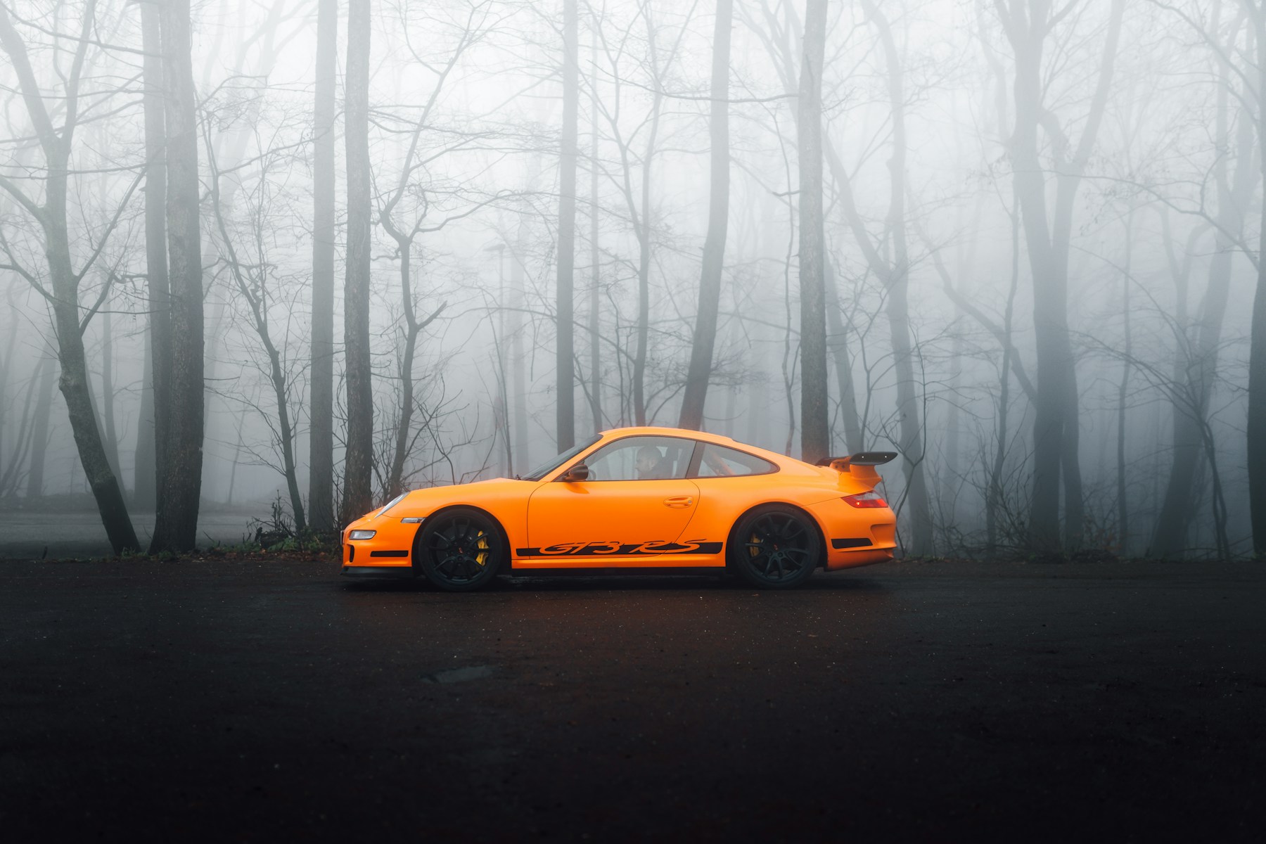 Oranje Porsche 911 GT3 RS op een bosweg